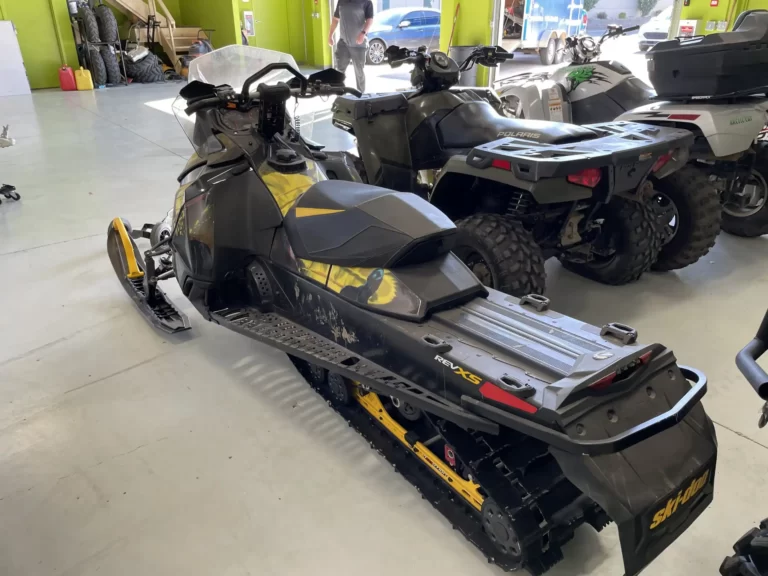 The snowmobiles are parked in a garage.